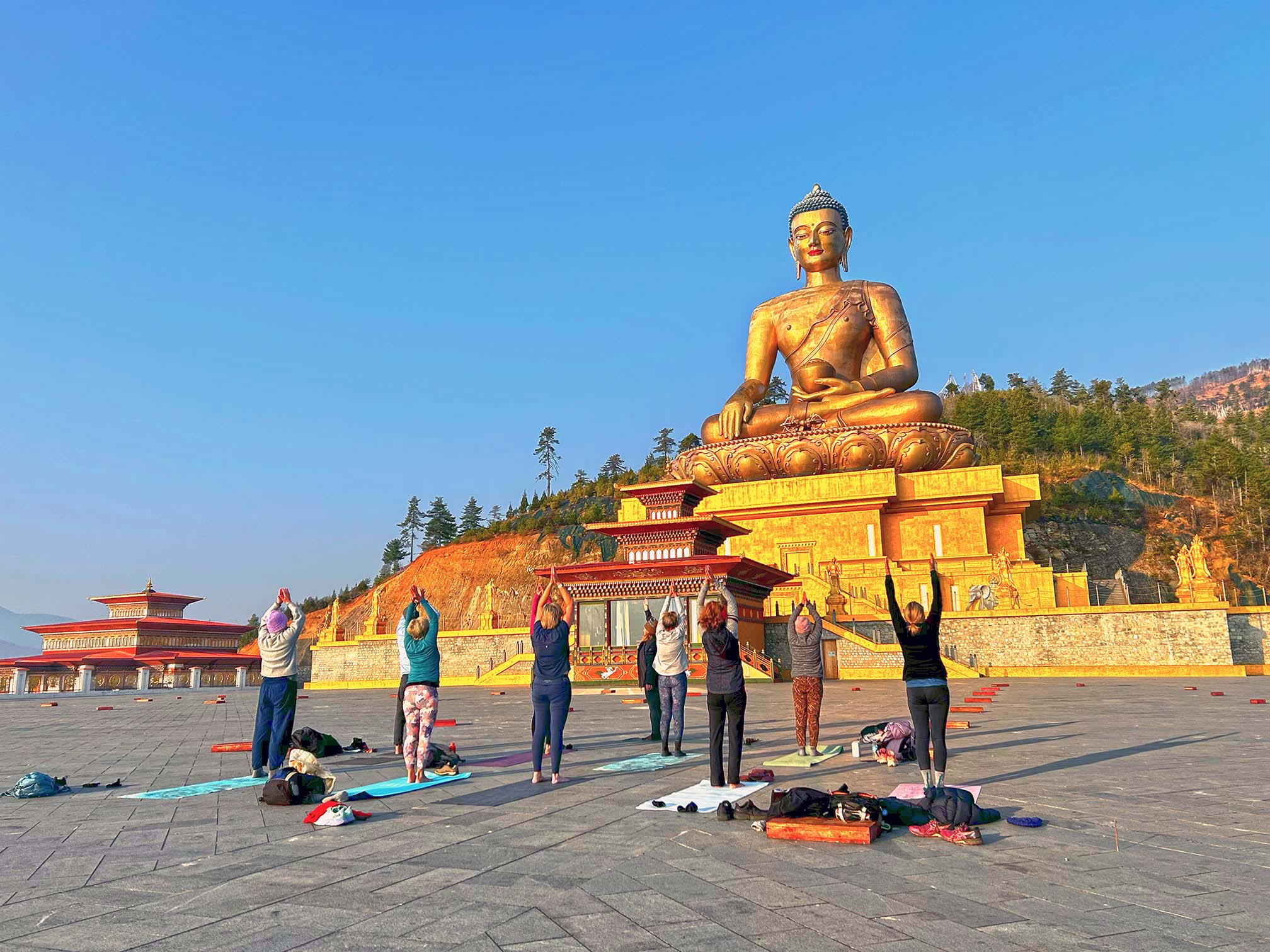 Yoga session at sunrise in front of a 54-meter-tall bronze and gold-gilded statue of Shakyamuni Buddha in Thimphu Bhutan